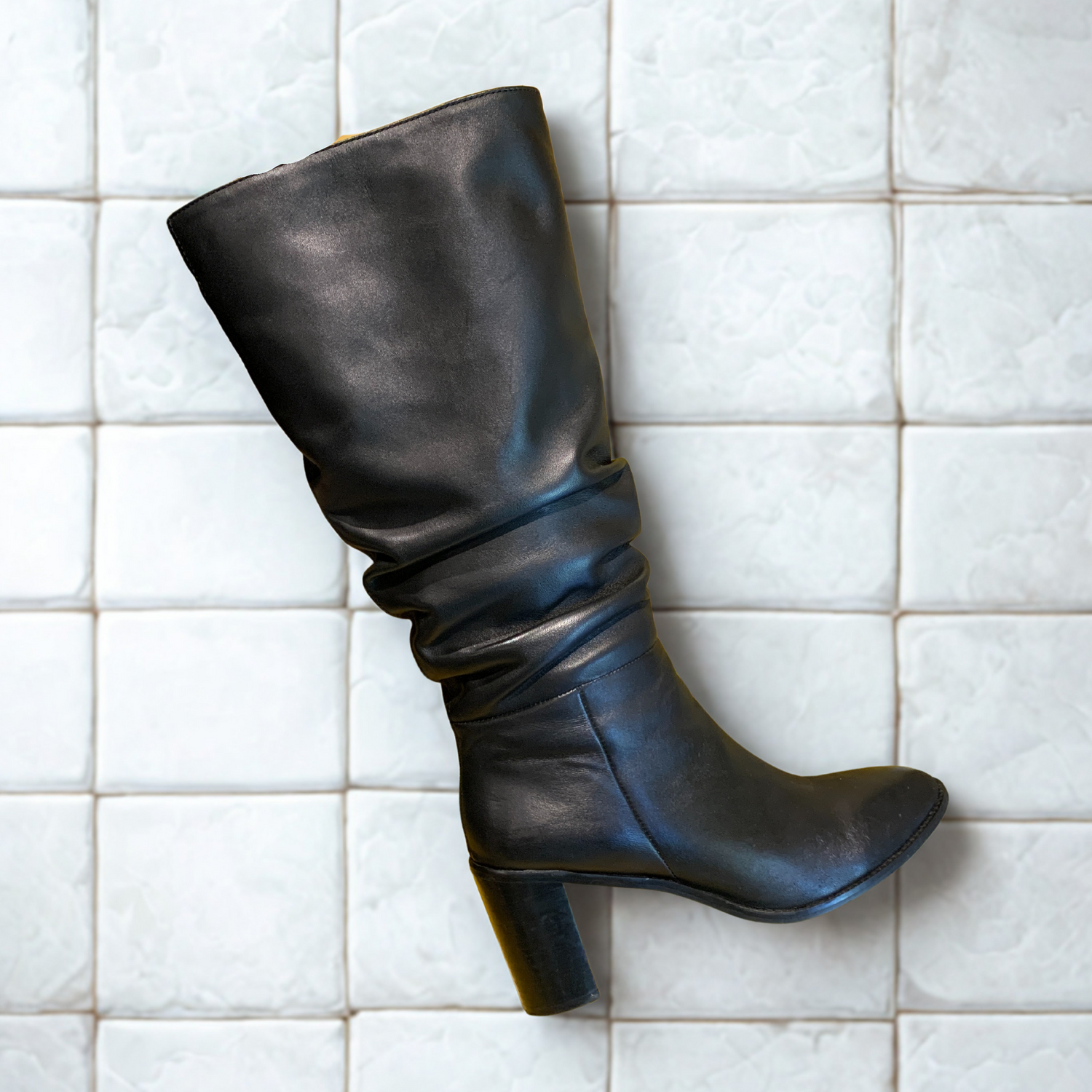 Black leather boot on a white tiled floor